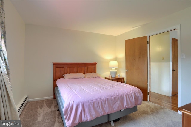 bedroom with a baseboard heating unit and light carpet