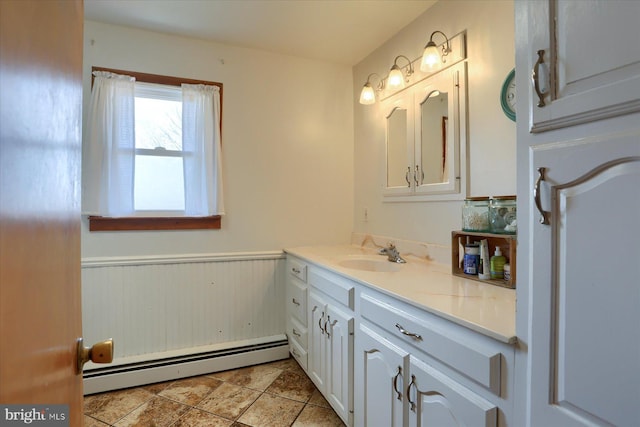 bathroom with a wainscoted wall, baseboard heating, and vanity