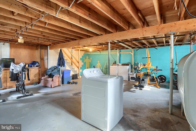 unfinished below grade area featuring concrete block wall, stairs, and washer and dryer