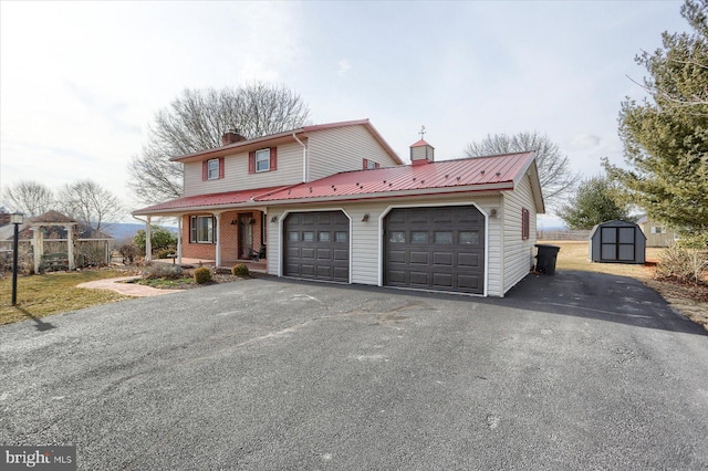 view of front of property featuring a garage, driveway, a chimney, and a shed