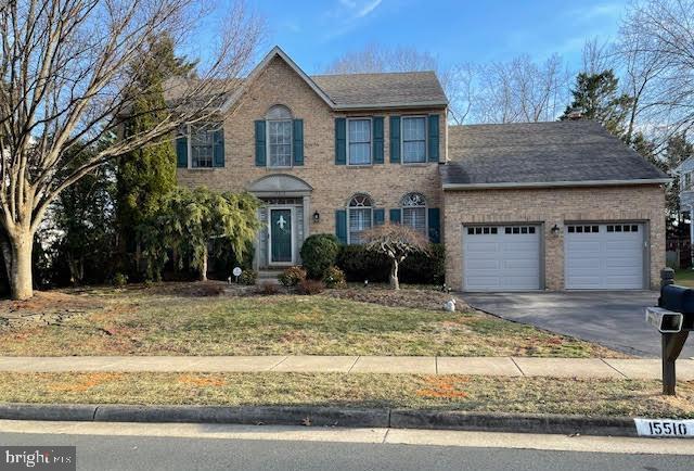 colonial home with a front yard, brick siding, driveway, and an attached garage