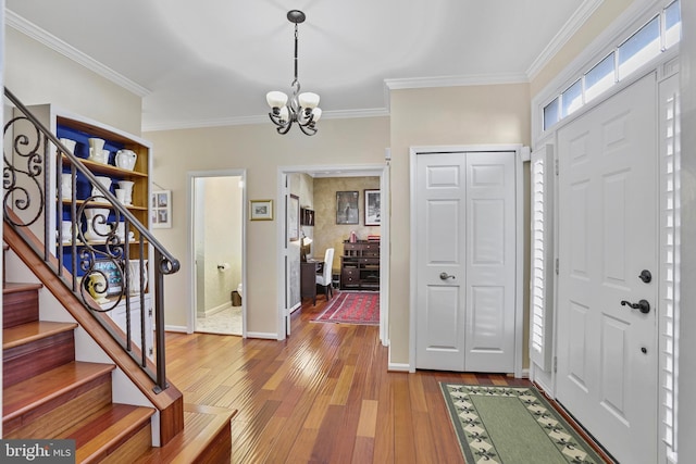 entryway featuring baseboards, stairway, ornamental molding, hardwood / wood-style floors, and a chandelier