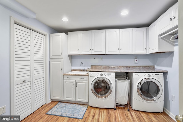 washroom with light wood finished floors, independent washer and dryer, a sink, and cabinet space