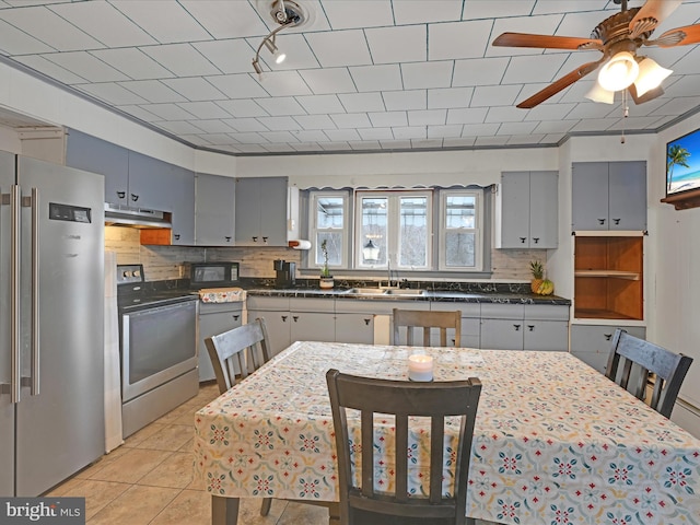 kitchen with stainless steel appliances, dark countertops, backsplash, and under cabinet range hood