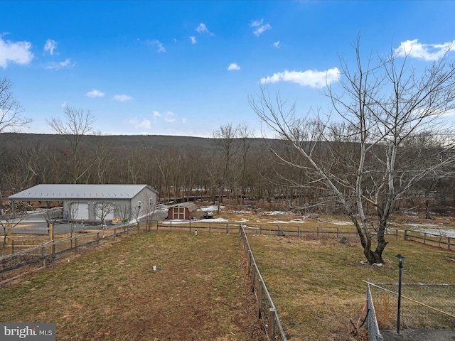 view of yard featuring an outbuilding, a rural view, and fence