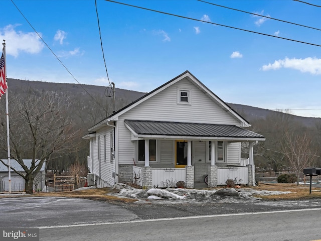 view of front facade featuring metal roof, a porch, and stone siding