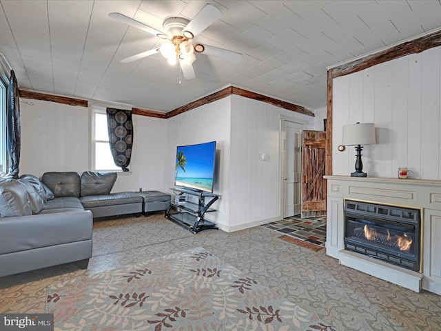 living area featuring a glass covered fireplace, ceiling fan, and baseboards