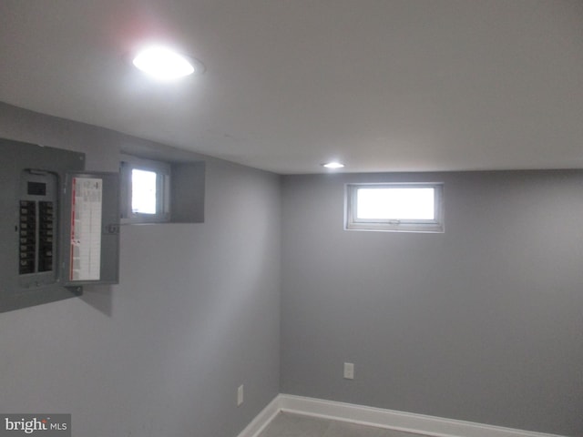 basement featuring recessed lighting, electric panel, a healthy amount of sunlight, and baseboards