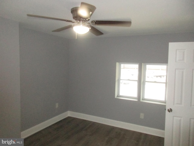 empty room featuring baseboards, dark wood finished floors, and a ceiling fan