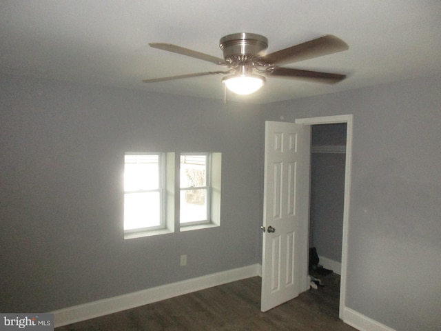 unfurnished bedroom featuring dark wood-style floors, ceiling fan, baseboards, and a closet