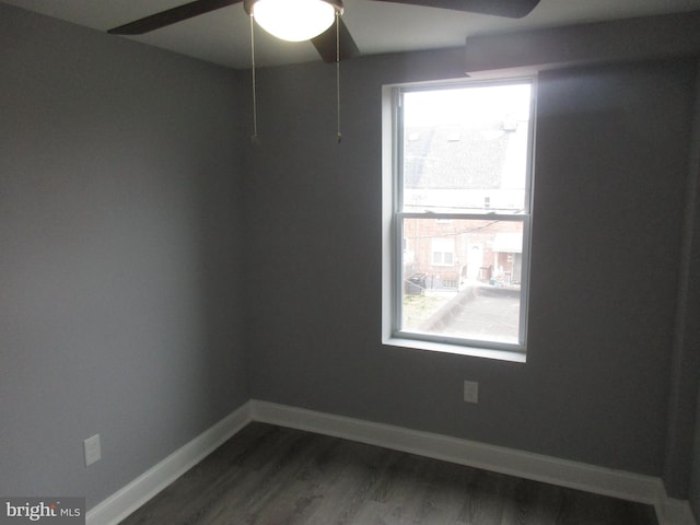 spare room featuring dark wood-style flooring and baseboards