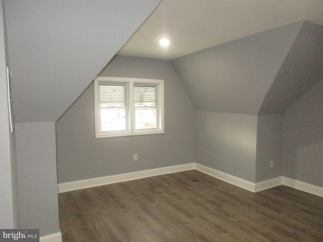 additional living space featuring dark wood-style floors, lofted ceiling, and baseboards