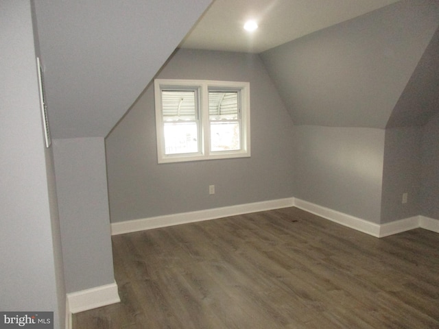 additional living space with lofted ceiling, dark wood-style flooring, and baseboards