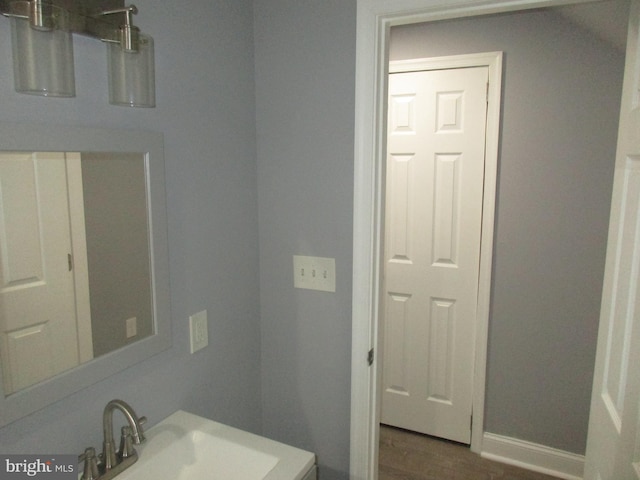 bathroom with a sink, baseboards, and wood finished floors