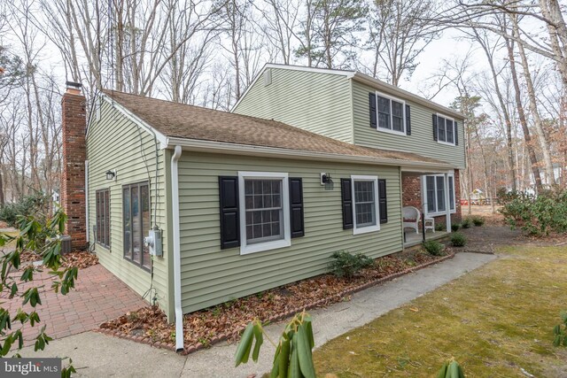 view of side of home featuring a chimney and a patio area