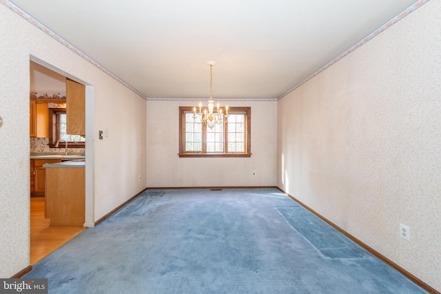 spare room with light carpet, a notable chandelier, crown molding, and wallpapered walls