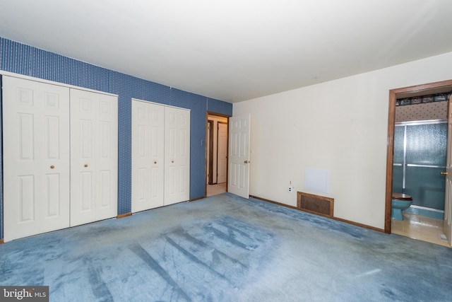 unfurnished bedroom with carpet flooring, baseboards, multiple closets, ensuite bath, and visible vents