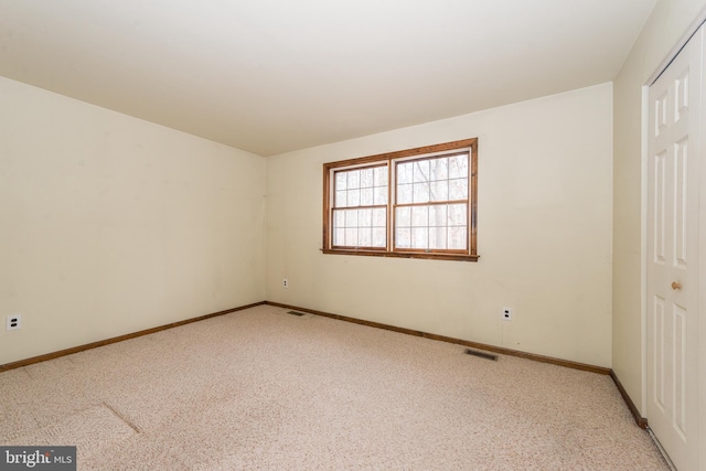 unfurnished bedroom with baseboards, a closet, light colored carpet, and visible vents