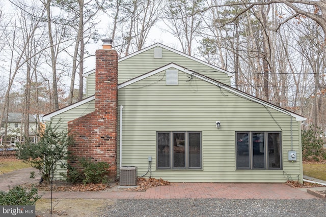back of house with a patio, central air condition unit, and a chimney