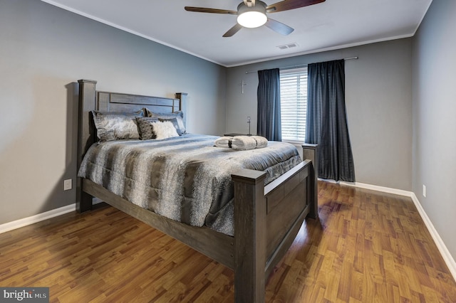 bedroom featuring visible vents, crown molding, and wood finished floors