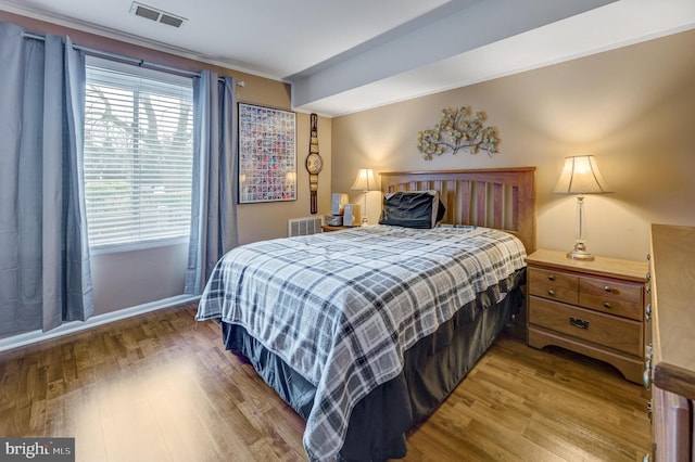 bedroom with visible vents, baseboards, and wood finished floors