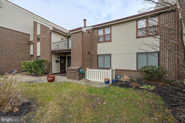 rear view of house with a yard, a patio, and brick siding