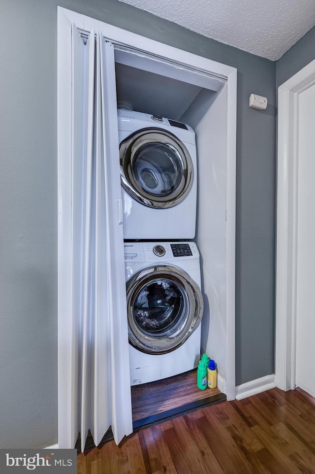 washroom featuring a textured ceiling, wood finished floors, laundry area, and stacked washer / dryer