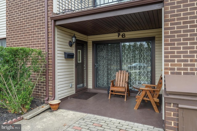 doorway to property featuring brick siding and a balcony