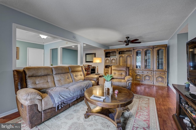 living area with baseboards, ceiling fan, ornamental molding, wood finished floors, and a textured ceiling