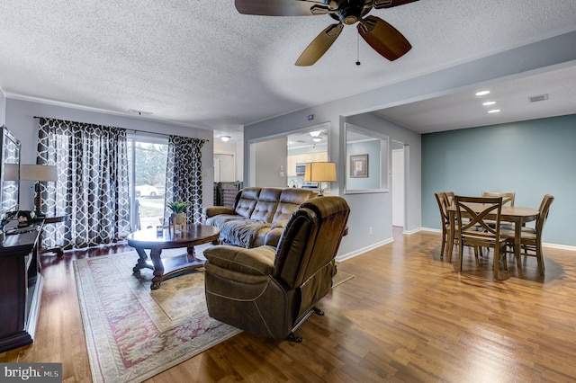 living area featuring baseboards, wood finished floors, visible vents, and a textured ceiling