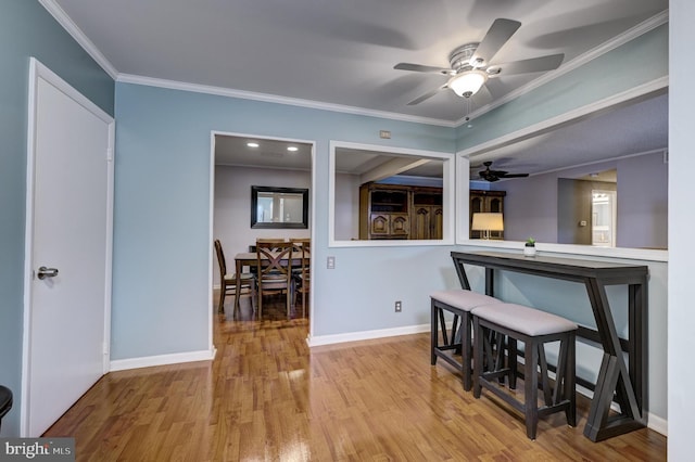 dining area featuring baseboards, wood finished floors, a ceiling fan, and ornamental molding