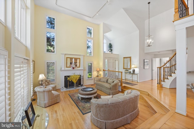 living room featuring a high ceiling, a fireplace with flush hearth, a wealth of natural light, and wood finished floors