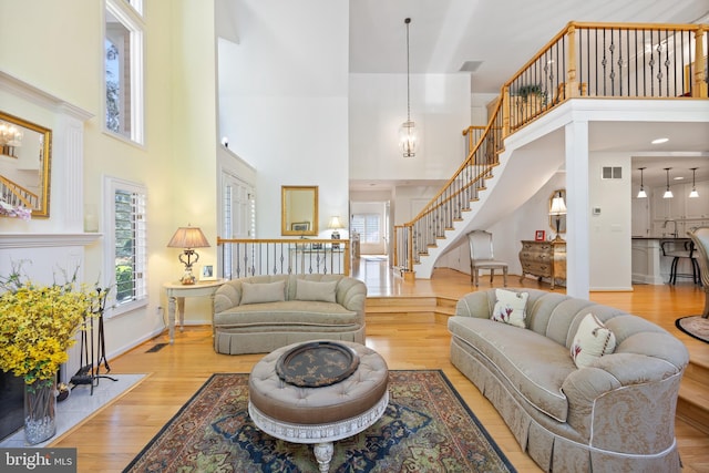 living room featuring a wealth of natural light, visible vents, a high ceiling, and stairs