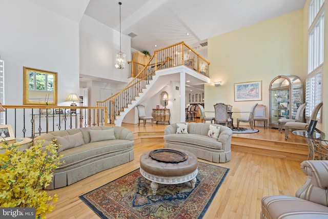 living room featuring recessed lighting, hardwood / wood-style floors, stairs, and a high ceiling