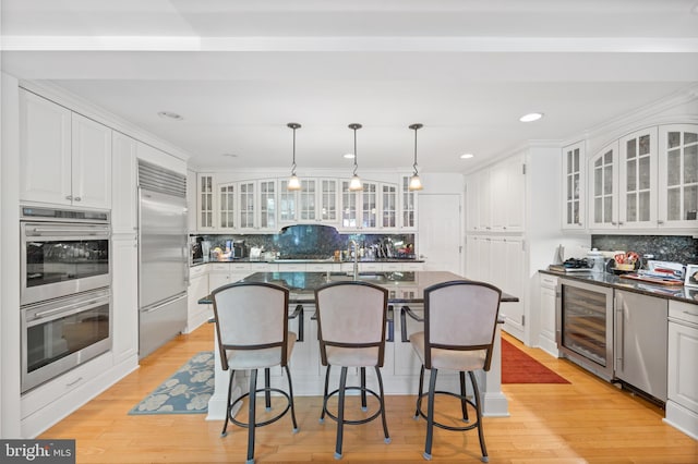 kitchen with white cabinets, tasteful backsplash, stainless steel appliances, and beverage cooler