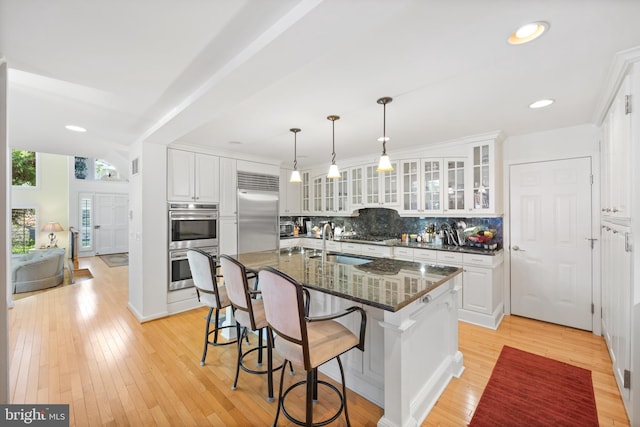 kitchen featuring white cabinetry, tasteful backsplash, stainless steel appliances, and a kitchen breakfast bar