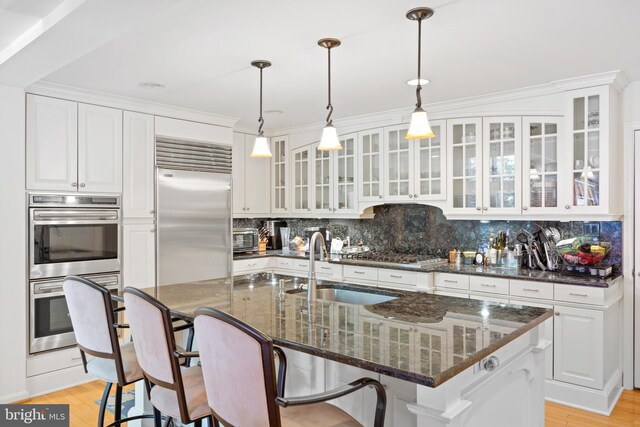kitchen featuring white cabinetry, backsplash, appliances with stainless steel finishes, and a sink