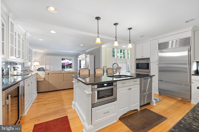 kitchen featuring a sink, white cabinetry, stainless steel appliances, and beverage cooler
