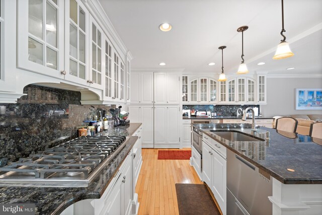 kitchen with white cabinetry, stainless steel appliances, decorative backsplash, and a sink