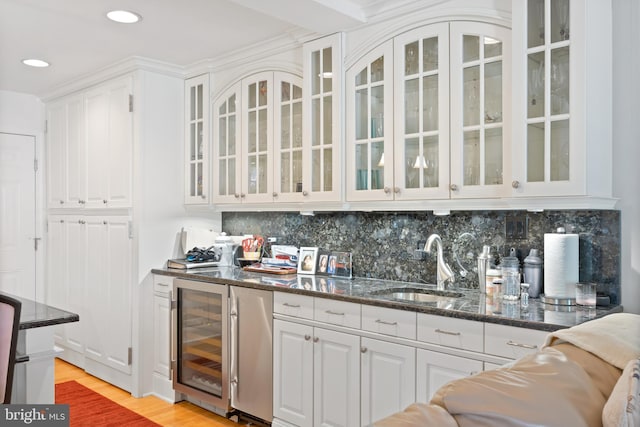 bar with recessed lighting, decorative backsplash, light wood finished floors, a sink, and wine cooler