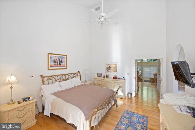 bedroom with light wood-type flooring and a high ceiling