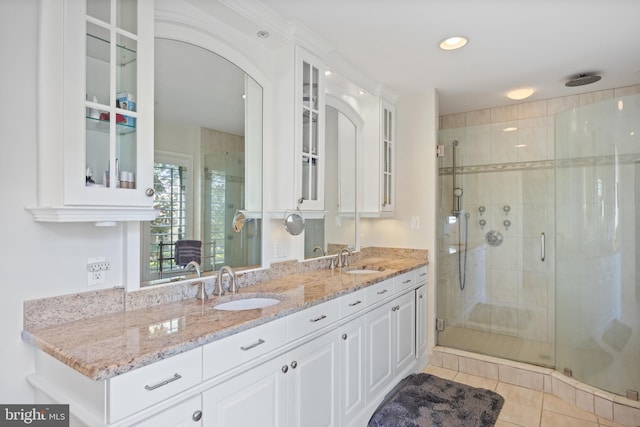 full bathroom with tile patterned floors, a stall shower, double vanity, and a sink