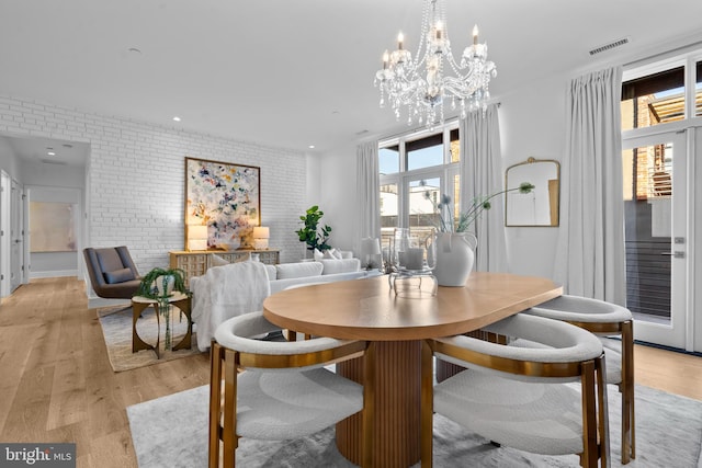 dining space featuring light wood-style flooring, recessed lighting, visible vents, and brick wall