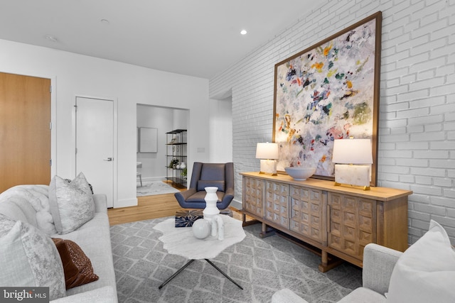 sitting room featuring recessed lighting, brick wall, baseboards, and wood finished floors