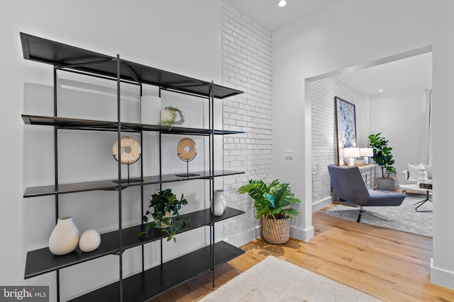 interior space with recessed lighting, baseboards, wood finished floors, and brick wall