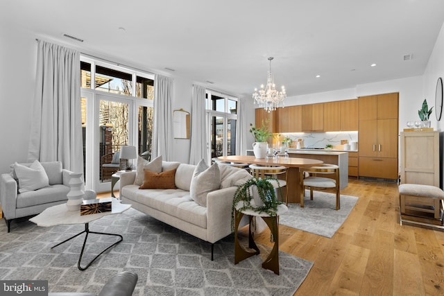 living room featuring recessed lighting, visible vents, a notable chandelier, and light wood finished floors