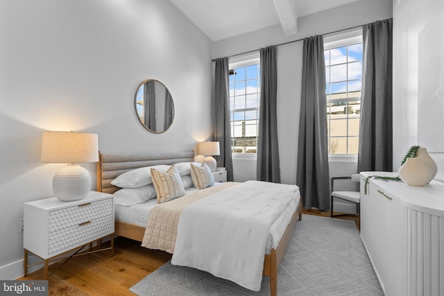 bedroom featuring lofted ceiling with beams and wood finished floors