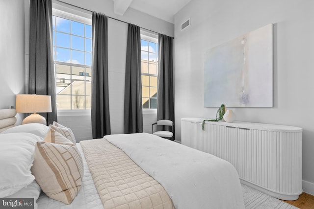 bedroom featuring visible vents, radiator, and beamed ceiling