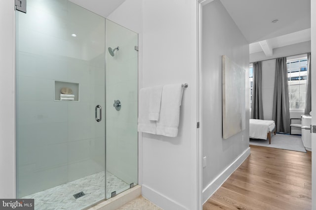 bathroom featuring baseboards, wood finished floors, and a shower stall