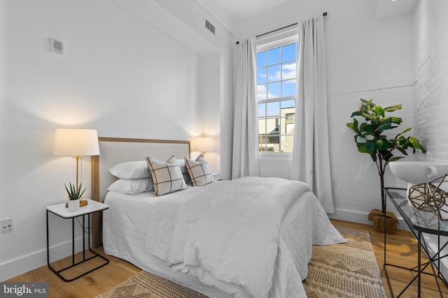 bedroom with visible vents, baseboards, and wood finished floors